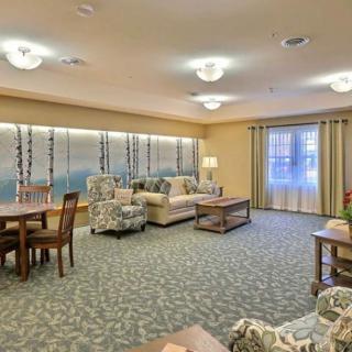 A spacious and well-lit living room with comfortable seating and a patterned carpet.