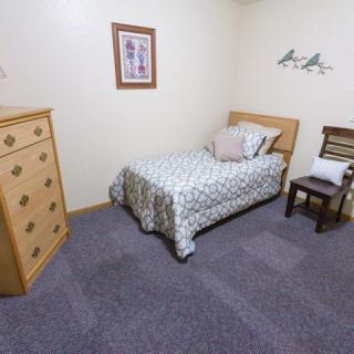 A small bedroom with a single bed, dresser, and chair.