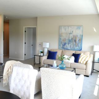 A modern living room with stylish decor featuring a sofa, armchairs, and artwork on the wall.