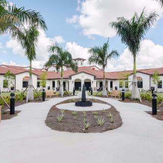 A scenic view of a building surrounded by palm trees, featuring a central pathway leading to a fountain.