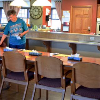 A woman prepares a dining area by setting the table.