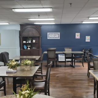 A cozy dining area featuring wooden tables and chairs, adorned with floral decor against a calming blue wall.