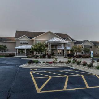 A modern building with a parking lot in front, surrounded by landscaped grounds.