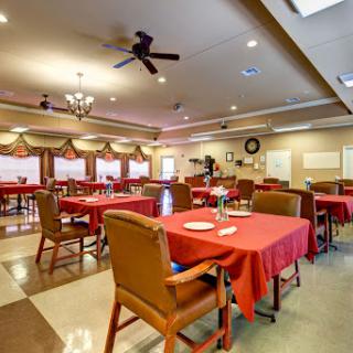 A spacious dining area featuring tables set with red tablecloths, illuminated by soft lighting.