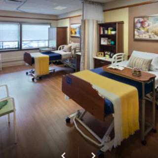 A clean and well-organized hospital room with two beds and medical equipment.