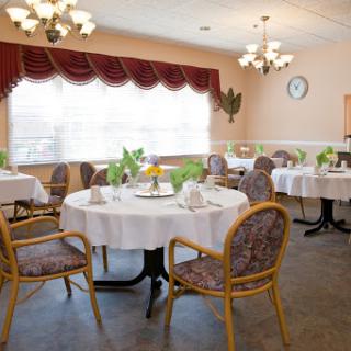 A cozy dining room set up with neatly arranged tables and chairs, illuminated by soft lighting.