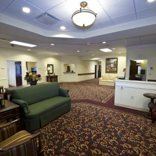 A spacious lobby area with a green sofa, patterned carpet, and a reception desk.