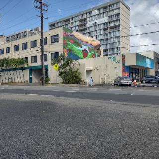 A vibrant mural adorns a building in an urban setting, showcasing public art amidst everyday street life.