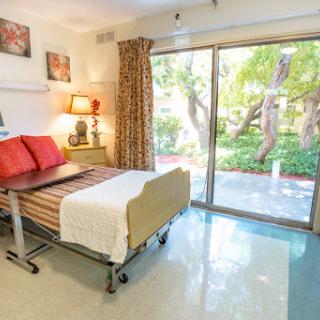 A well-lit hospital room featuring a comfortable bed and a view of the garden, designed for patient comfort and care.