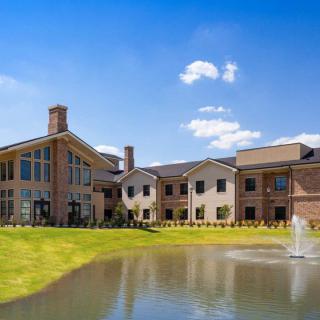 A scenic view of a modern building with a pond and fountain in the foreground.