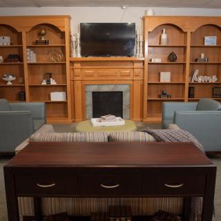 A cozy living room with a fireplace, wooden bookshelves, and comfortable seating.