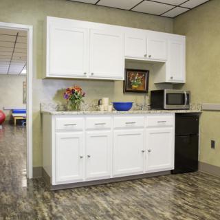 A modern kitchen area with white cabinets, a microwave, and decorative items on the countertop.