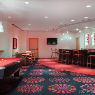 A modern game room featuring a pool table and bar seating with vibrant decor.