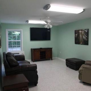 A cozy living room with green walls, featuring a couch, TV, and framed artwork.