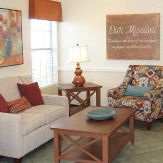 A cozy living room featuring a comfortable sofa and a colorful armchair, complemented by decorative artwork and a warm ambiance.