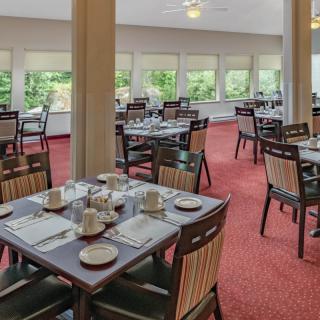 A spacious dining area with neatly arranged tables and chairs, surrounded by large windows.