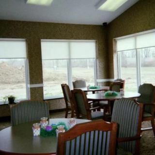 A cozy dining area with several tables and chairs, featuring large windows with views of the outdoors.