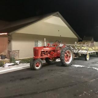 A red tractor parked next to a building at night.