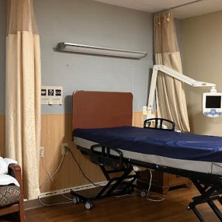 A clean and organized hospital patient room featuring a bed and medical equipment.