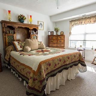 A cozy, traditional bedroom with a quilted bedspread and decorative pillows.