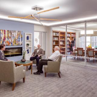 A modern office lounge area with comfortable seating, a bookshelf, and a collaborative atmosphere.
