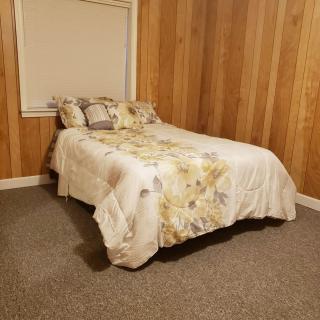 A cozy bedroom with wood-paneled walls and a neatly made bed.