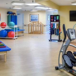 A well-equipped fitness room with exercise bikes, therapy balls, and rehabilitation equipment.