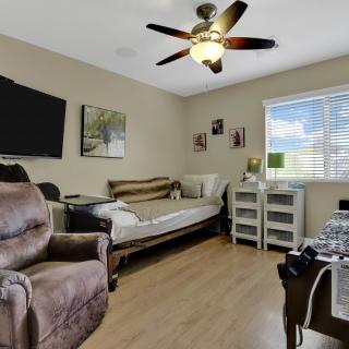 A cozy bedroom with a recliner, daybed, and ceiling fan.