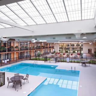A spacious indoor pool area in a hotel, featuring comfortable seating and ample natural light.