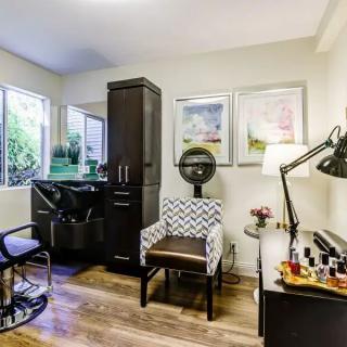 A cozy beauty salon equipped with a styling chair, dryer, and manicure station.