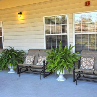 Outdoor porch with cushioned benches and potted plants.