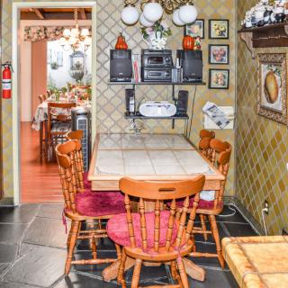 A cozy kitchen dining area featuring a wooden table and chairs, surrounded by vintage decor and wall art.