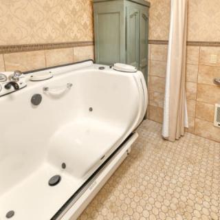 A bathroom featuring a large bathtub with a shower curtain and tiled walls.