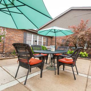 A cozy outdoor patio setup featuring a table and chairs with green umbrellas, perfect for enjoying a meal in the fresh air.