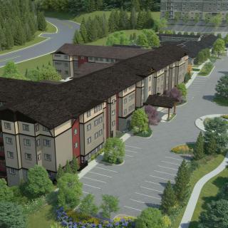 Aerial view of an apartment complex with a spacious parking lot surrounded by greenery and trees.