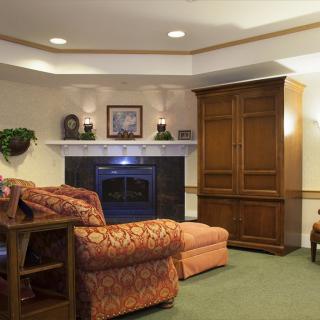 A cozy living room with a fireplace, comfortable seating, and elegant wooden furniture.