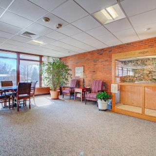 A spacious office interior featuring a meeting area with large windows, comfortable seating, and decorative plants.