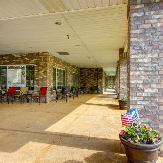 A covered patio area with brick walls, outdoor seating, and a flower pot displaying an American flag.