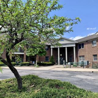 A brick building with a tree in the foreground and a clear blue sky.