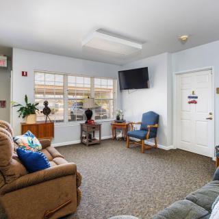 A cozy living room with couches, a chair, and a wall-mounted television.