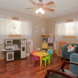A cozy children's playroom featuring a colorful table and chairs set, a kitchen playset, and toys on display.