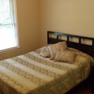 A cozy bedroom with a bed and pillows near a window.