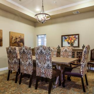 A well-decorated dining room with a large table, upholstered chairs, and a chandelier.