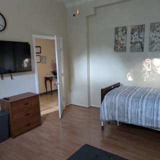 A cozy bedroom featuring a single bed, television, and decorative artwork on the walls.