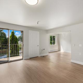 A bright and modern living room featuring a spacious layout with access to a balcony.