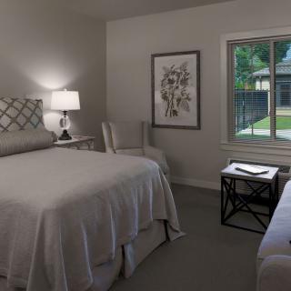 A cozy bedroom with a bed, lamp, and window view.