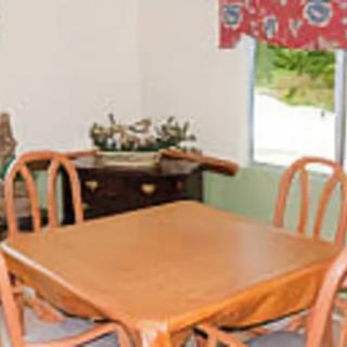 A cozy dining area with a wooden table and chairs next to a window with floral curtains.