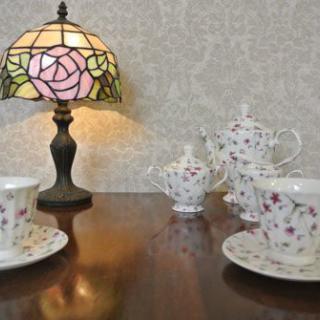A cozy setup featuring a floral tea set and a vintage lamp on a wooden table.