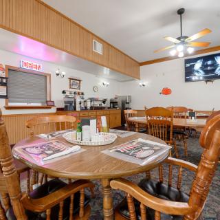 A cozy restaurant dining area featuring wooden tables and chairs, with a television mounted on the wall.