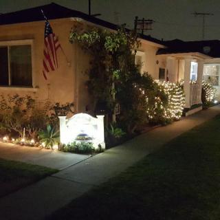 A house decorated with holiday lights at night, featuring an American flag.